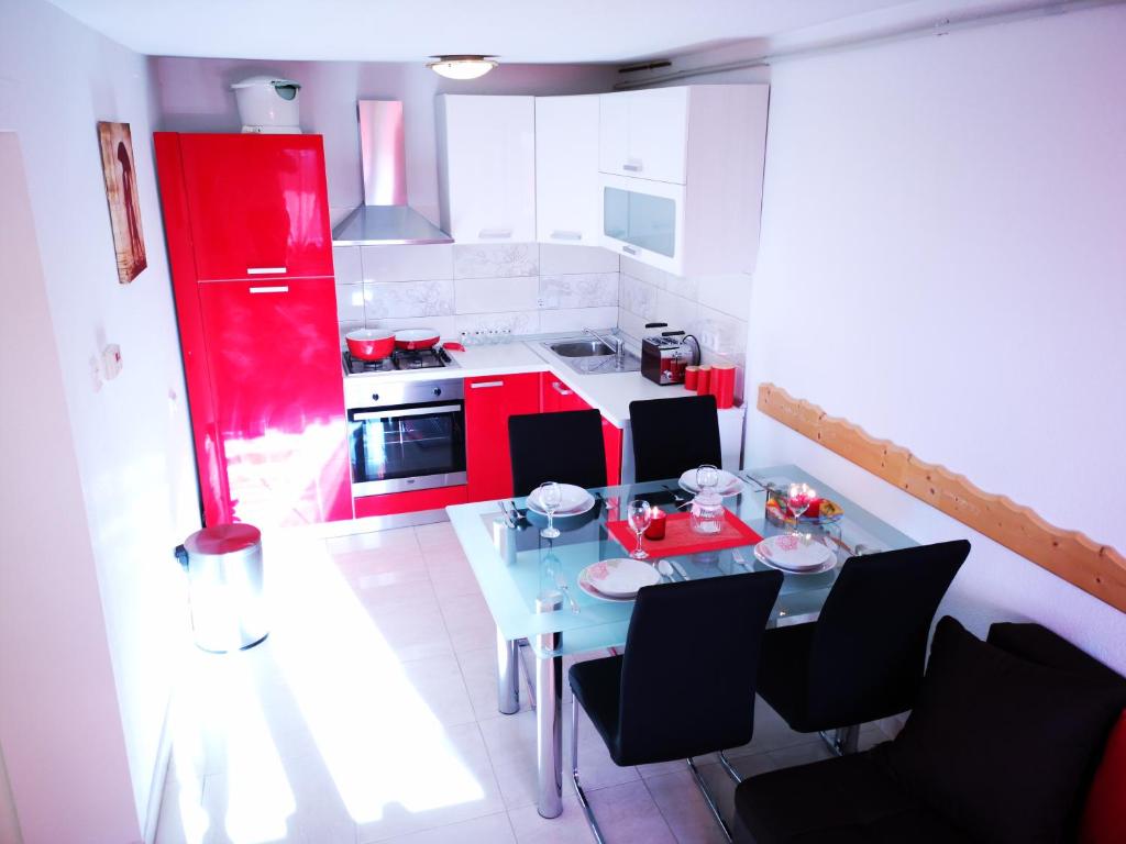 a kitchen with a table and chairs and red cabinets at Apartman "Sabine red" with pool in Omišalj