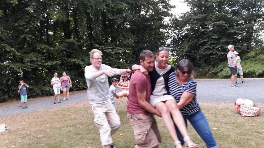 a group of people hugging each other in a park at Camping le Clos de Balleroy in Balleroy