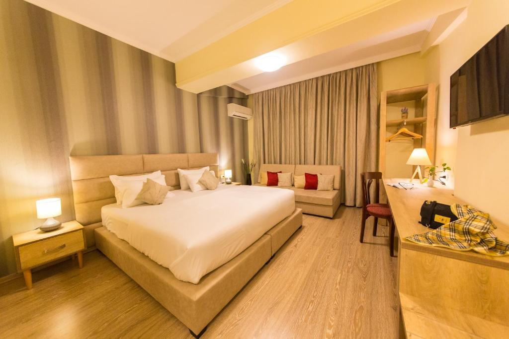 a hotel room with a bed and a couch at Hotel Baron in Tirana