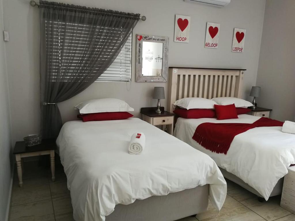 una camera con due letti con cuscini rossi e bianchi di Kalahari Rus a Upington