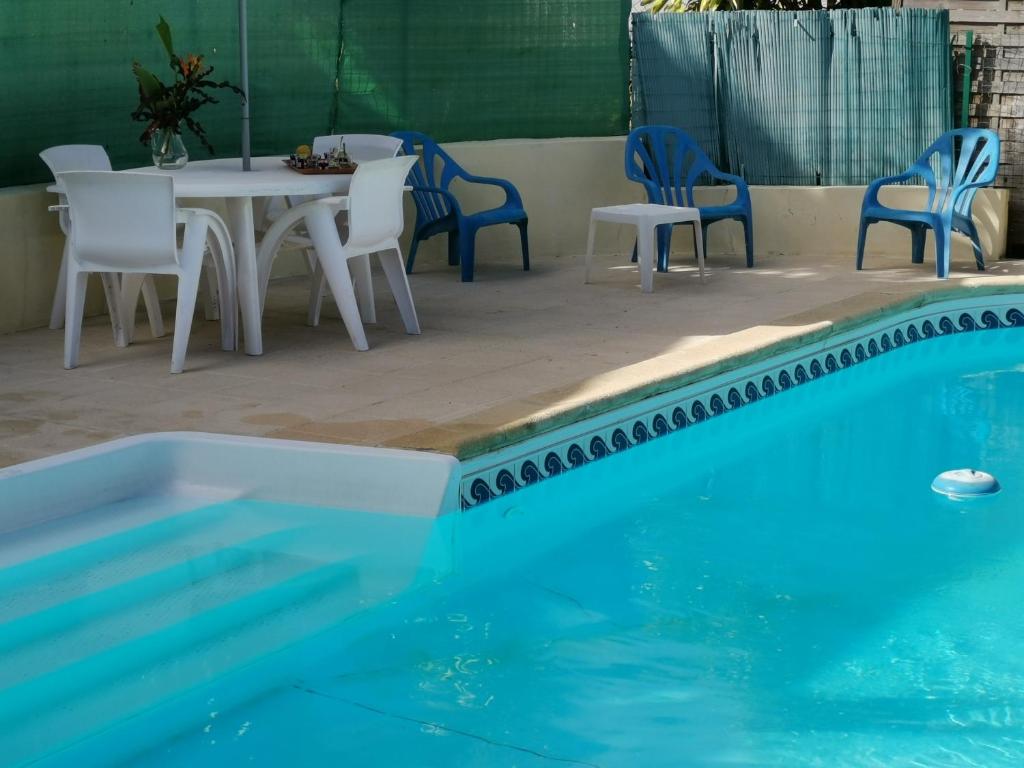una piscina azul con sillas, mesa, mesa y sillas en La citronnelle, en Sainte-Anne