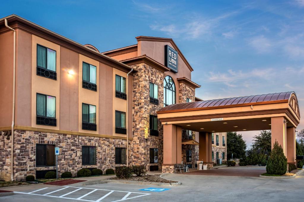 um hotel com um parque de estacionamento em frente em Red Lion Inn & Suites Mineral Wells em Mineral Wells