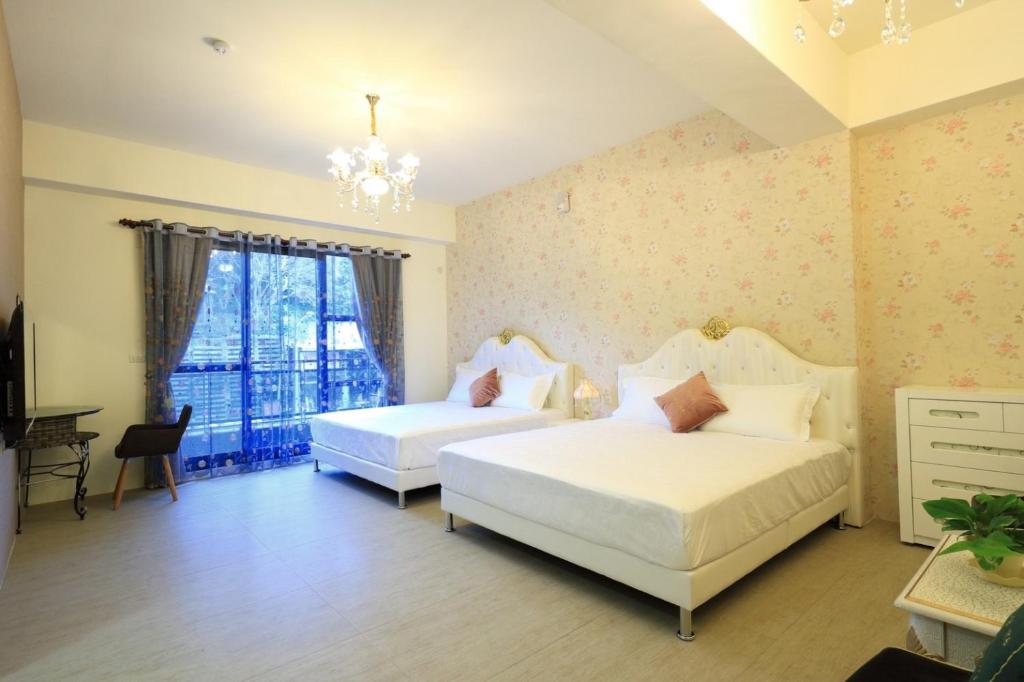 a bedroom with two beds and a chandelier at 花蓮漫漫時光電梯包棟民宿 in Hualien City