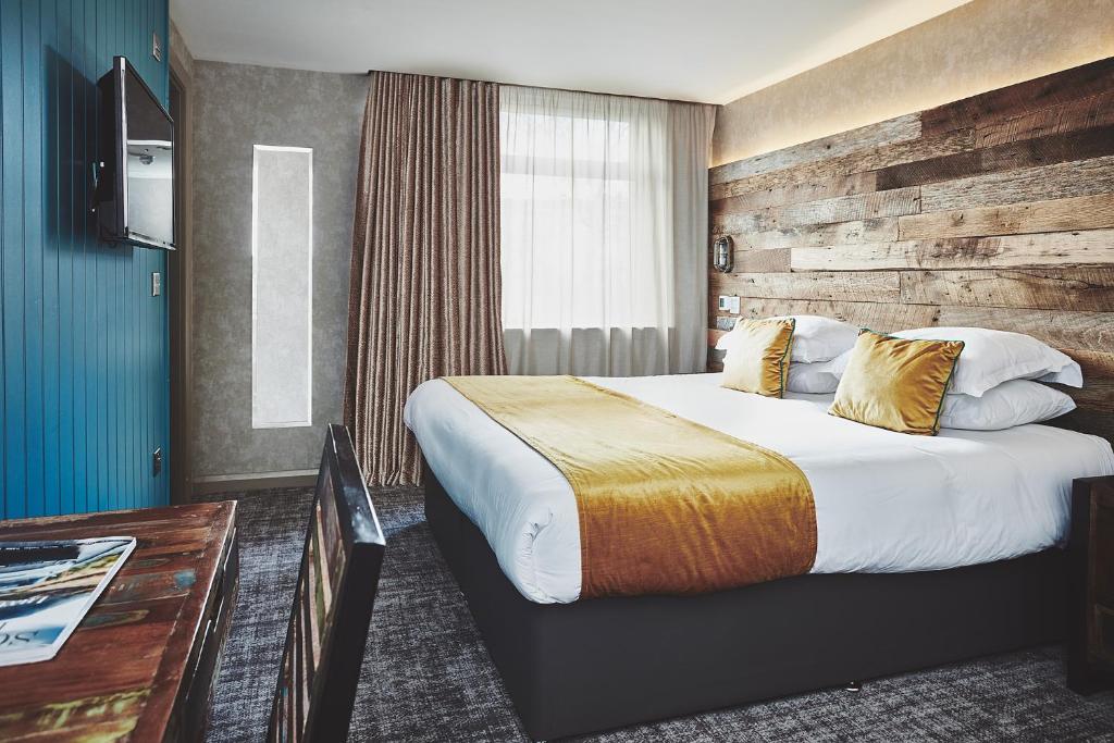 フォート・ウィリアムにあるThe Garrisonのベッドと木製の壁が備わるホテルルームです。
