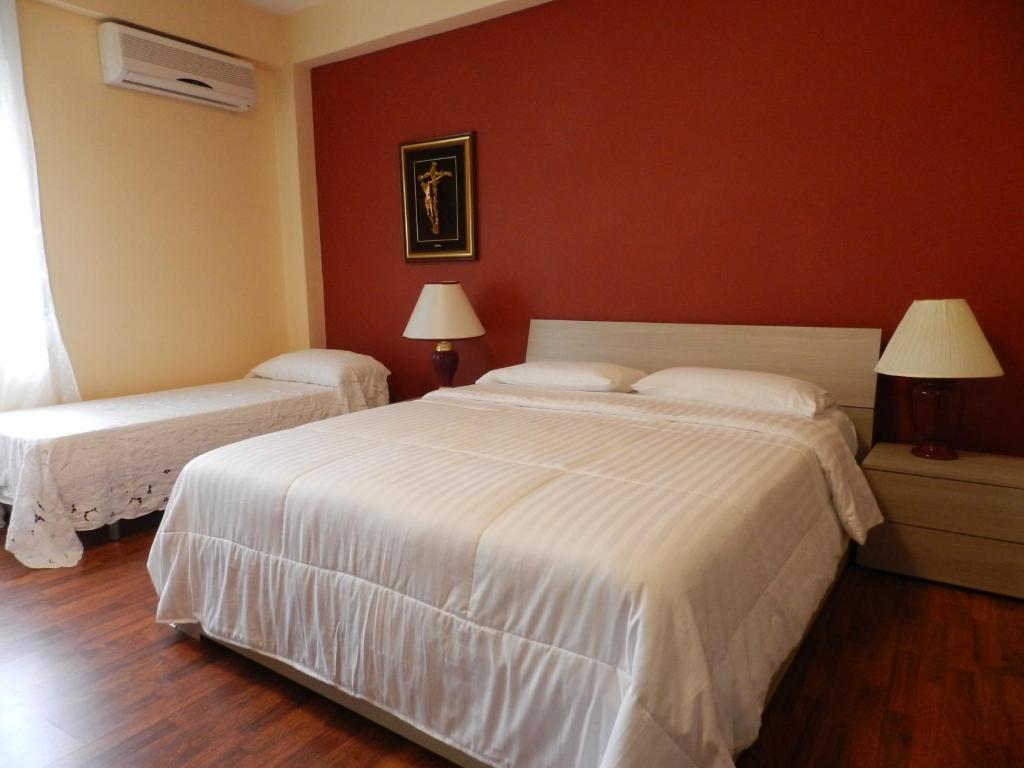 a bedroom with two beds and a red wall at B&B Joe in Valguarnera Caropepe