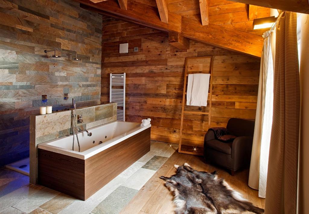 a bathroom with a tub in a room with wooden walls at Villa Kofler Wonderland Resort in Campitello di Fassa