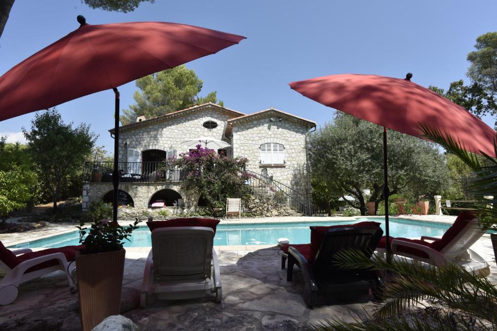 a pool with chairs and umbrellas in front of a house at Villa La Pastorale in Saint Paul de Vence