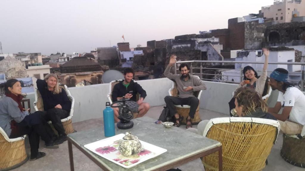 um grupo de pessoas sentadas em torno de uma mesa em um telhado em Bhavyam HomeStay &Cafe BackPackers ko em Bundi