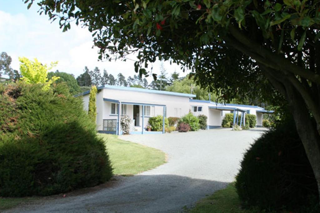 a white house with a driveway in front of it at Alma Motel in Oamaru