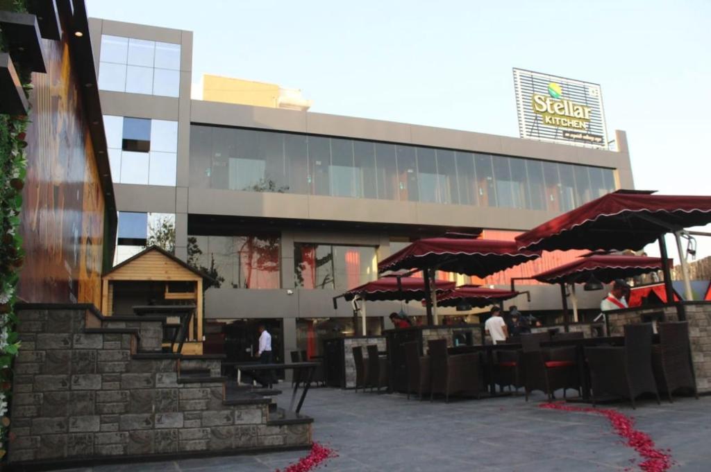 a building with tables and umbrellas in front of it at Hotel Stellar in Vadodara
