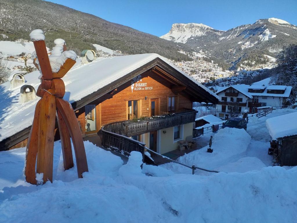 Cabaña de madera en la nieve con techo cubierto de nieve en Digart, en Ortisei