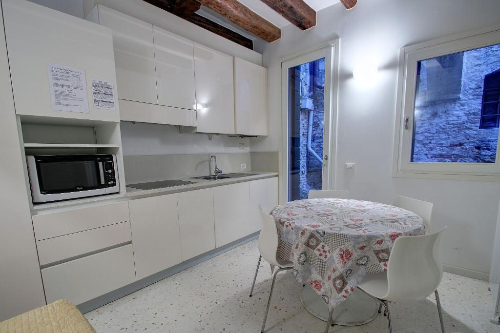 a kitchen with white cabinets and a table and chairs at Peggy in Venice