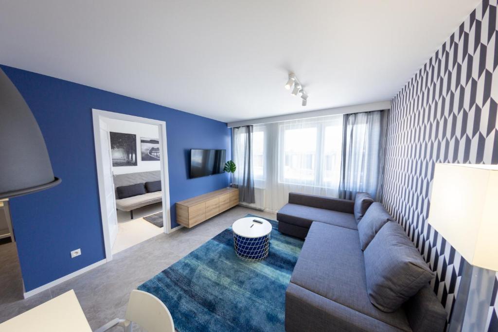 a living room with a couch and a blue wall at Apartamenty na Chopina in Kielce