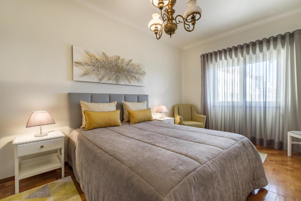Un dormitorio con una cama grande y una lámpara de araña. en Sea & Relax Villa Nazaré, en Nazaré