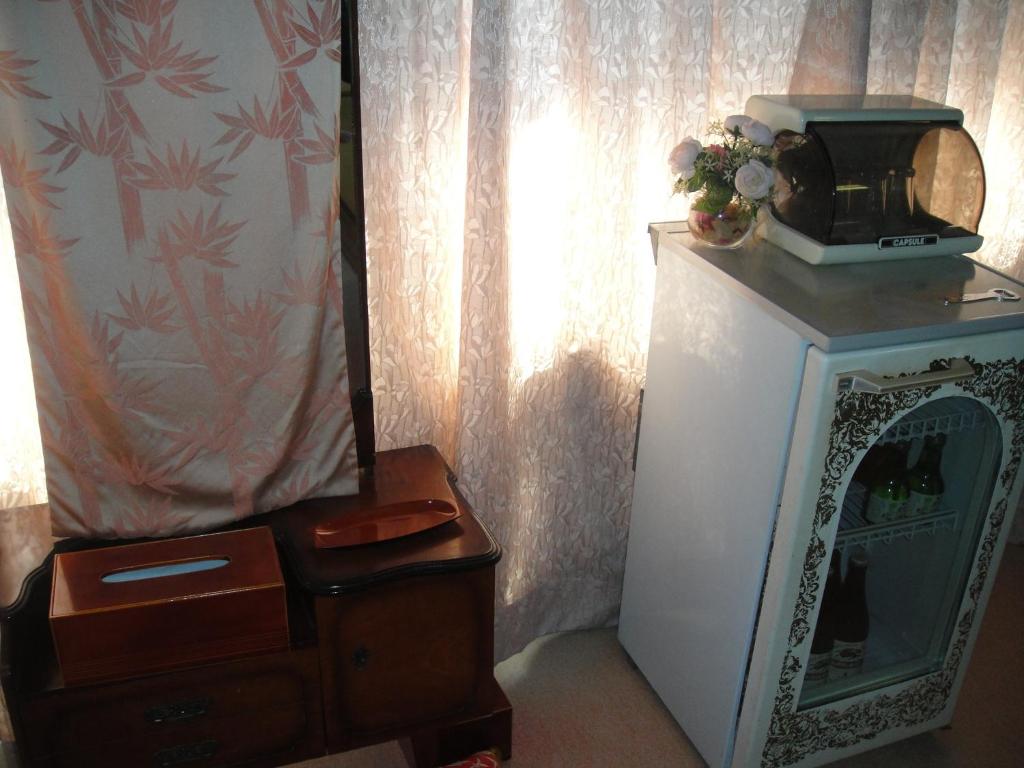 une chambre avec une télévision et un micro-ondes posé sur un réfrigérateur dans l'établissement Kurhaus Ishibashi Ryokan, à Shimoda