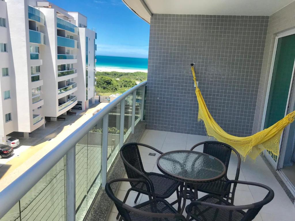 einen Balkon mit Stühlen, einer Hängematte und Meerblick in der Unterkunft Apartamento aconchegante vista mar e piscina em cond de Arraial do Cabo in Arraial do Cabo