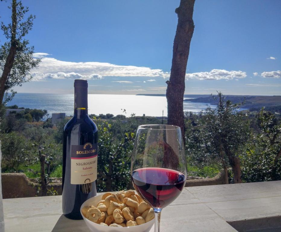 un bicchiere di vino accanto a una ciotola di noci di Bilocali Vista Mare a Santa Cesarea Terme