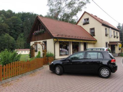 una macchina nera parcheggiata di fronte a una casa di Pension Strohbach a Sebnitz