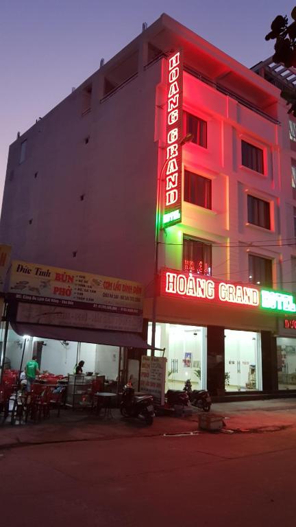 a hotel with a neon sign in front of it at Hoàng Grand in Cái Rồng