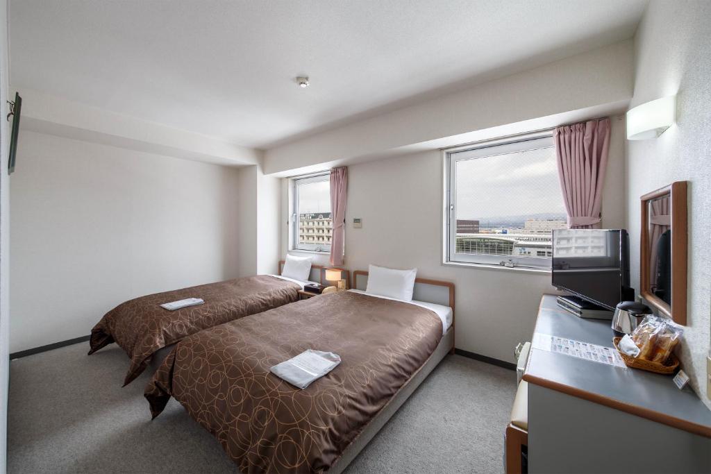 小松市にあるホテルエアポート小松のベッドとテレビが備わるホテルルームです。