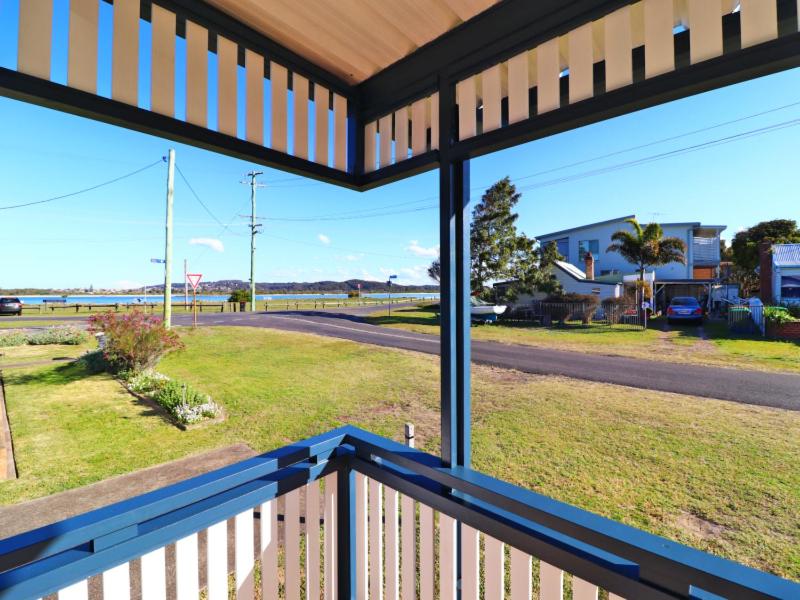 um alpendre com vista para uma estrada e um campo em Waterside Retreat - Blackies Beach - Swansea Channel em Blacksmiths