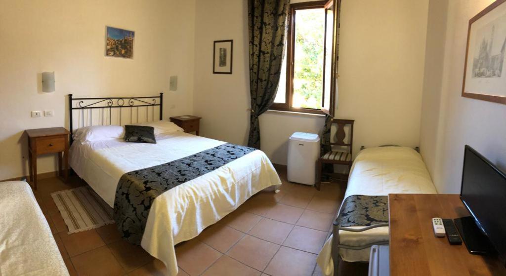 a bedroom with two beds and a desk and a television at Villa Tuscany Siena in Siena