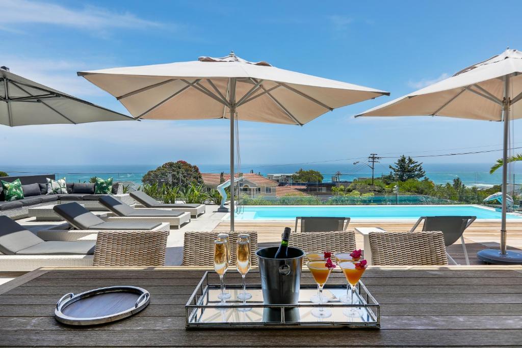 a table with drinks and umbrellas next to a pool at Jo Leo House by Totalstay in Cape Town