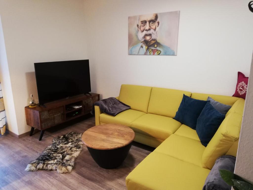 a living room with a yellow couch and a flat screen tv at Schmaranzer in Bad Ischl