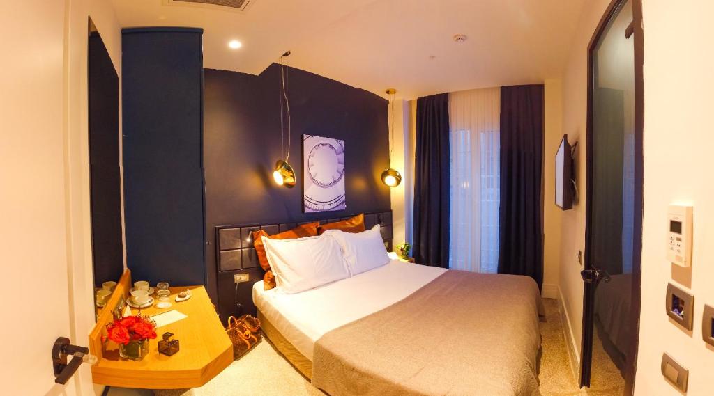 1 dormitorio con 1 cama y reloj en la pared en Maroon Tomtom, en Estambul