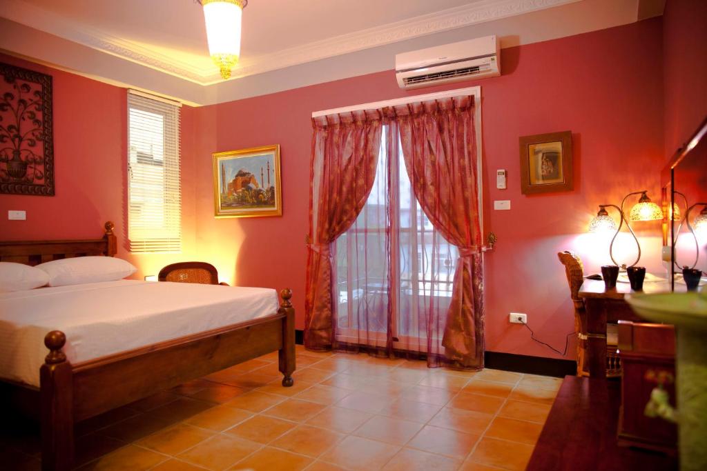 a bedroom with red walls and a bed and a window at Alongs Garden in Hengchun South Gate