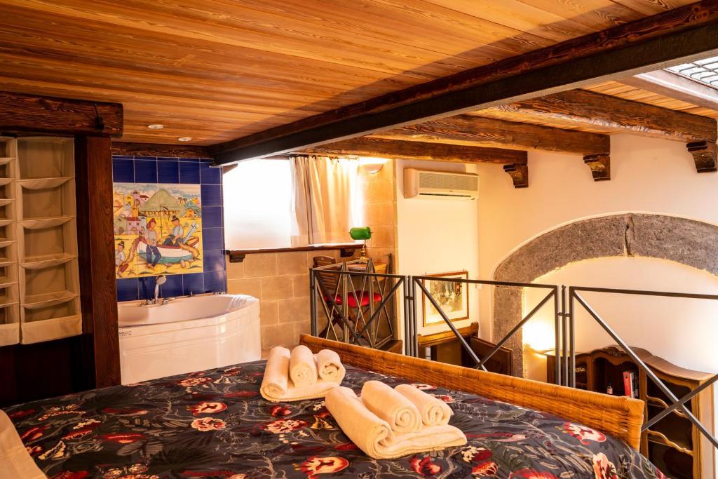 a bedroom with a tub and a bed with slippers at Suite Piazza del Gesù By DomusExtra in Naples