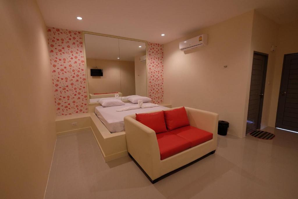 a bedroom with a bed and a red chair at Checkinn Resort Kanchanaburi in Kanchanaburi