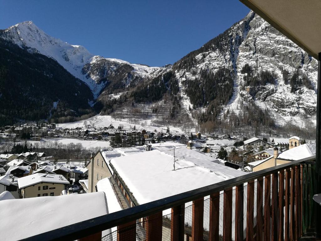 a view from a balcony of a town with snow covered mountains at L'Atelier du Temps - Appartamento CIRCE in Courmayeur