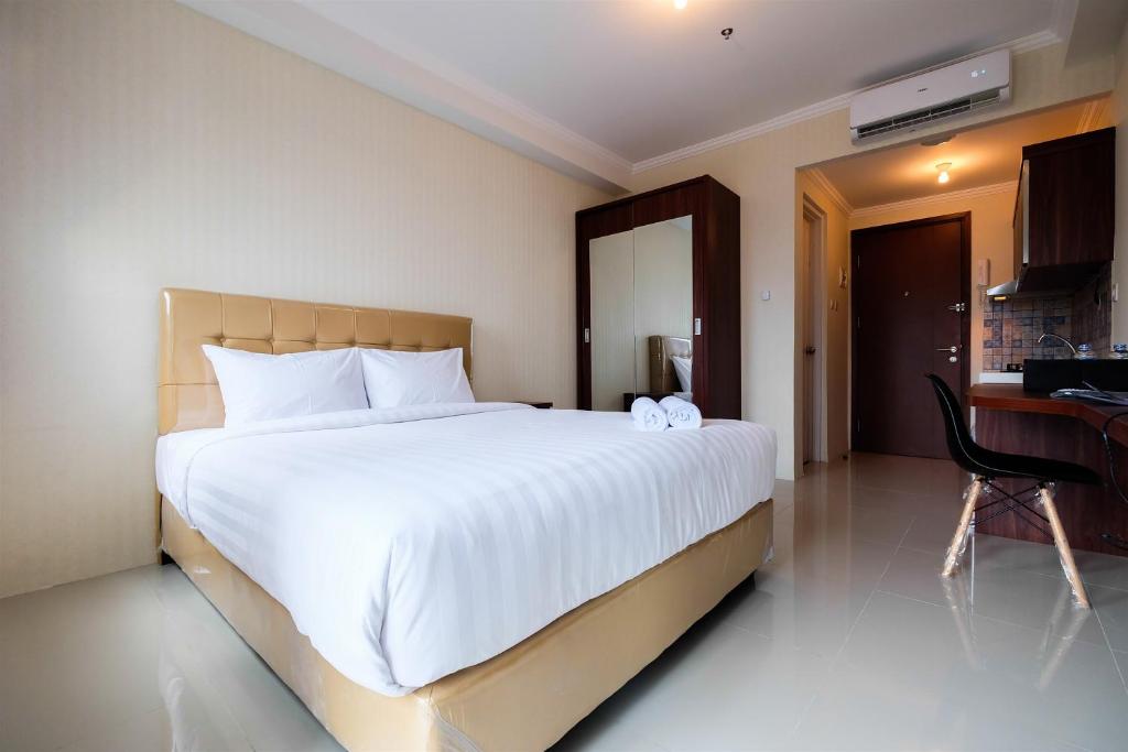 ジャカルタにあるSimple Studio Signature Park Grande Apartment near MT Haryono By Travelioの大きな白いベッドと机のある寝室