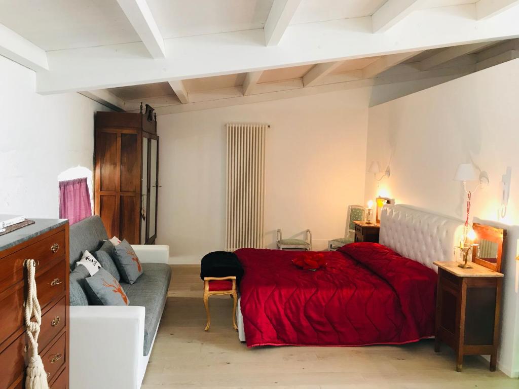 a bedroom with a red bed and a couch at B&B dell'orologio in Acquaviva delle Fonti