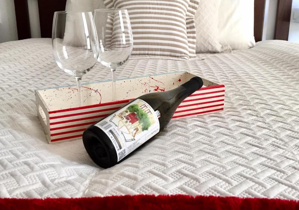 a bottle of wine and two glasses on a bed at A Coastine - alojamiento moderno para viajes de trabajo u ocio a Vigo y alrededores in Ponteareas