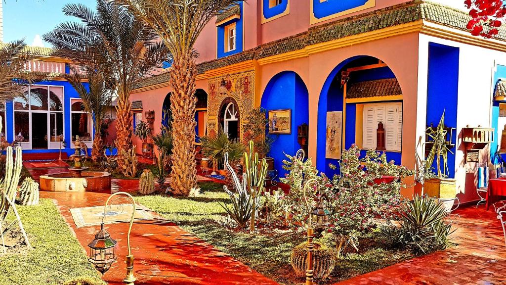 uma casa com paredes azuis e laranjas e palmeiras em Riad Jasmine Sud em Zagora
