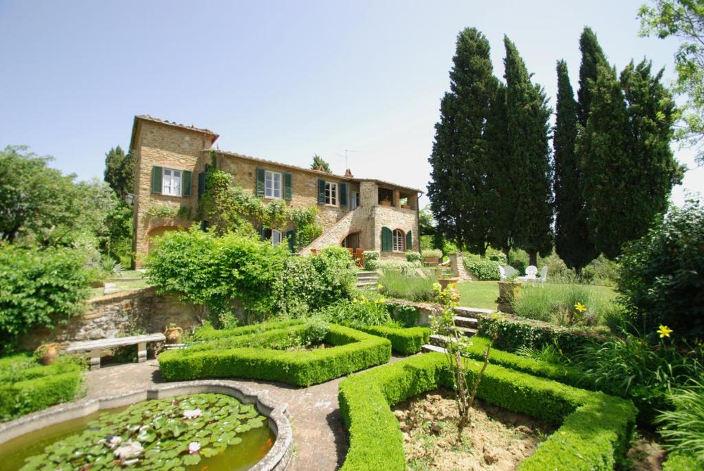 une maison avec un jardin et un étang en face de celle-ci dans l'établissement Il Giardino Inglese, à Lucignano