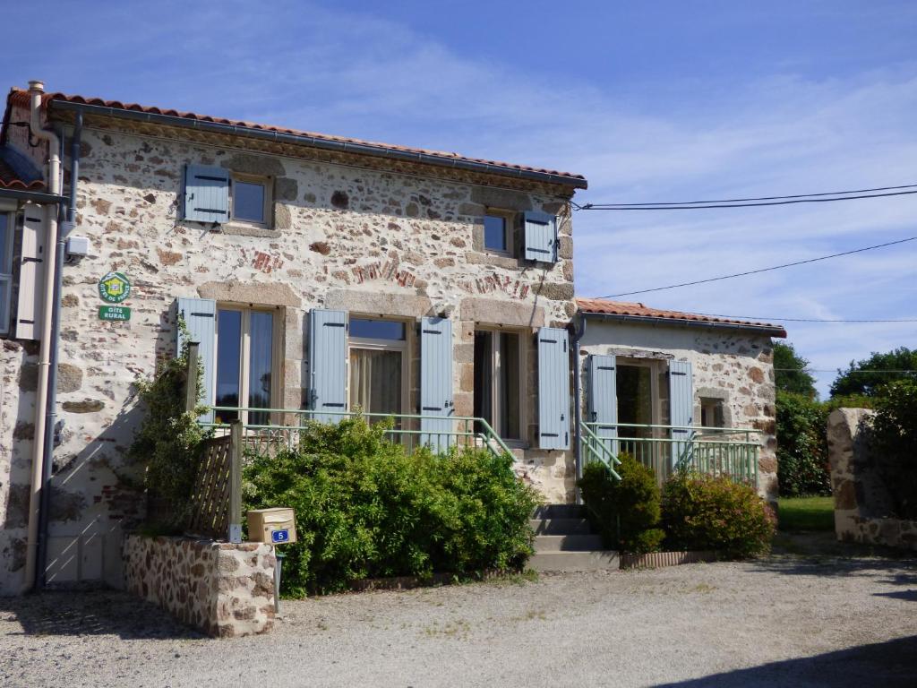 a stone house with blue shutters on a building at La Roseraie à 10min du Puy du fou in Saint-Mars-la-Réorthe