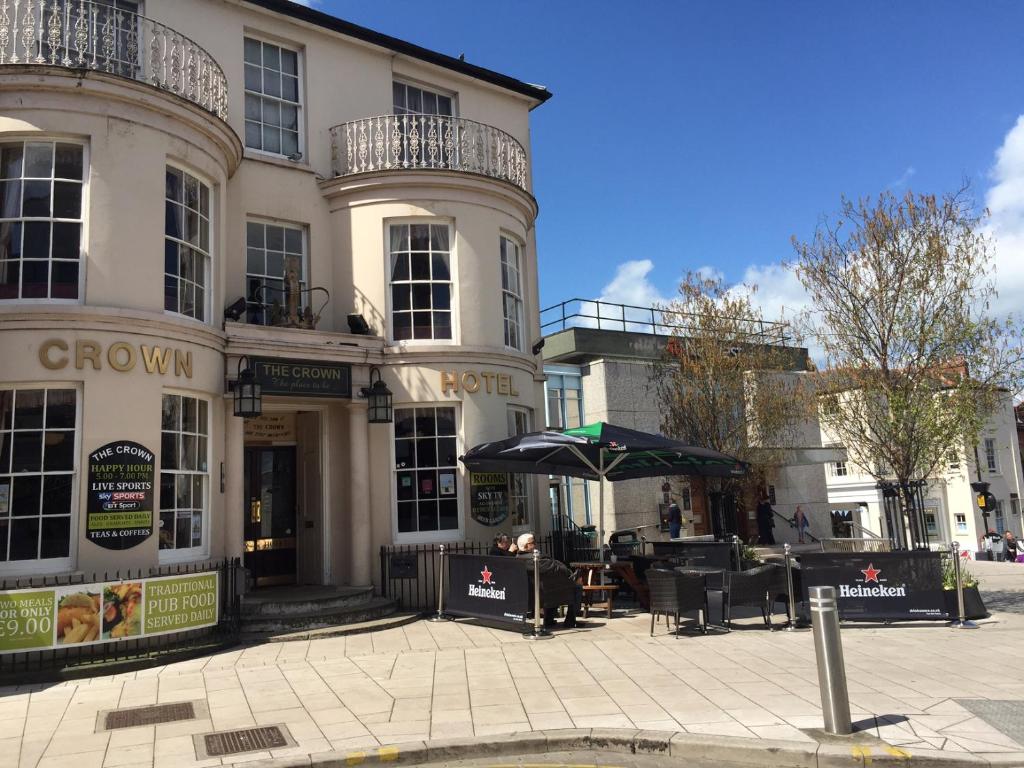 um edifício com uma mesa e um guarda-chuva em frente em The Crown Hotel em Ryde