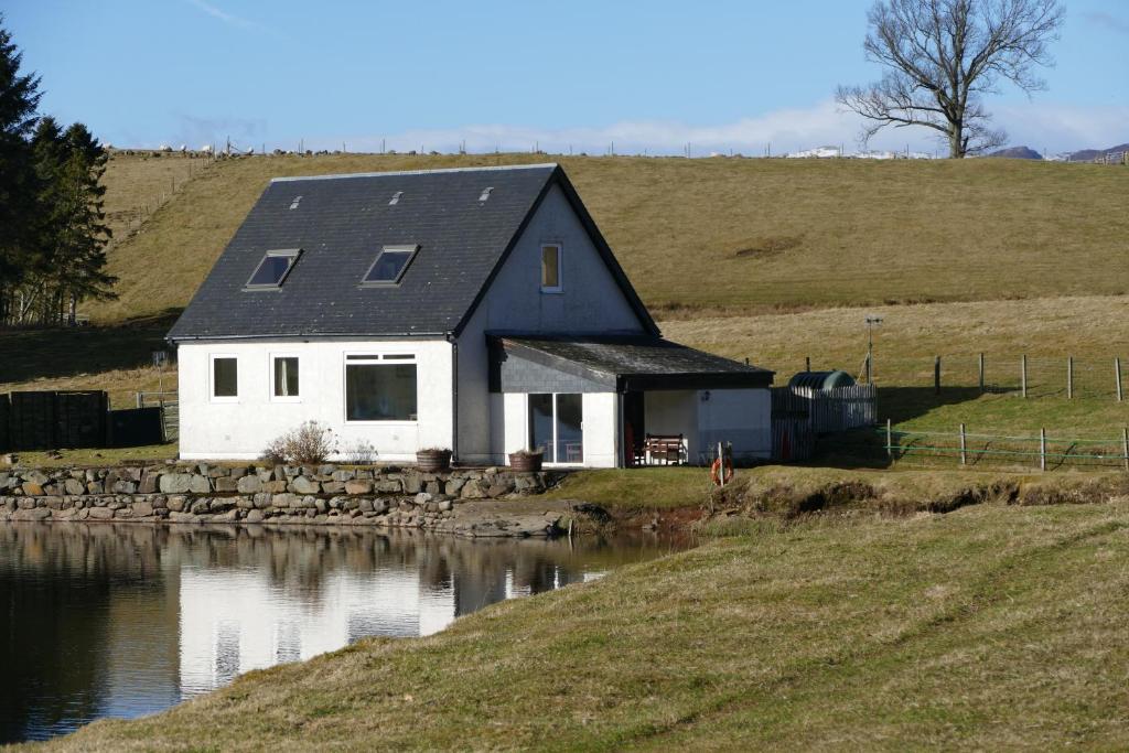 Wallace Lodge في كريف: منزل على تلة بجوار تجمع للمياه
