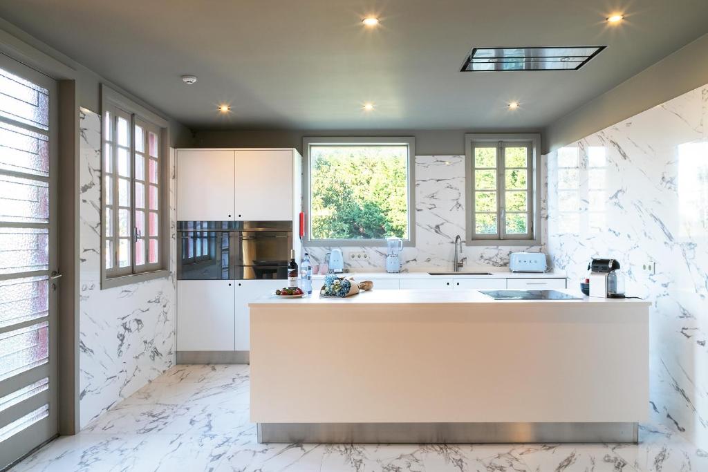 een keuken met witte marmeren muren en een groot eiland bij Slowly Garden House in Porto