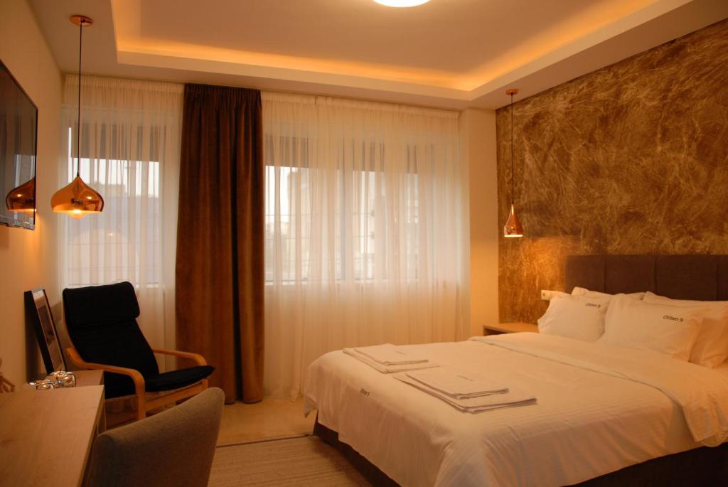 una camera d'albergo con un letto, una sedia e una finestra di citizen 9 a Salonicco