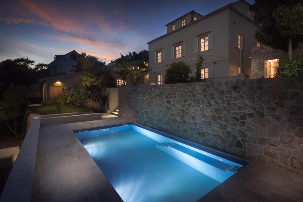 a swimming pool in front of a house at night at Villa Orti in Dubrovnik
