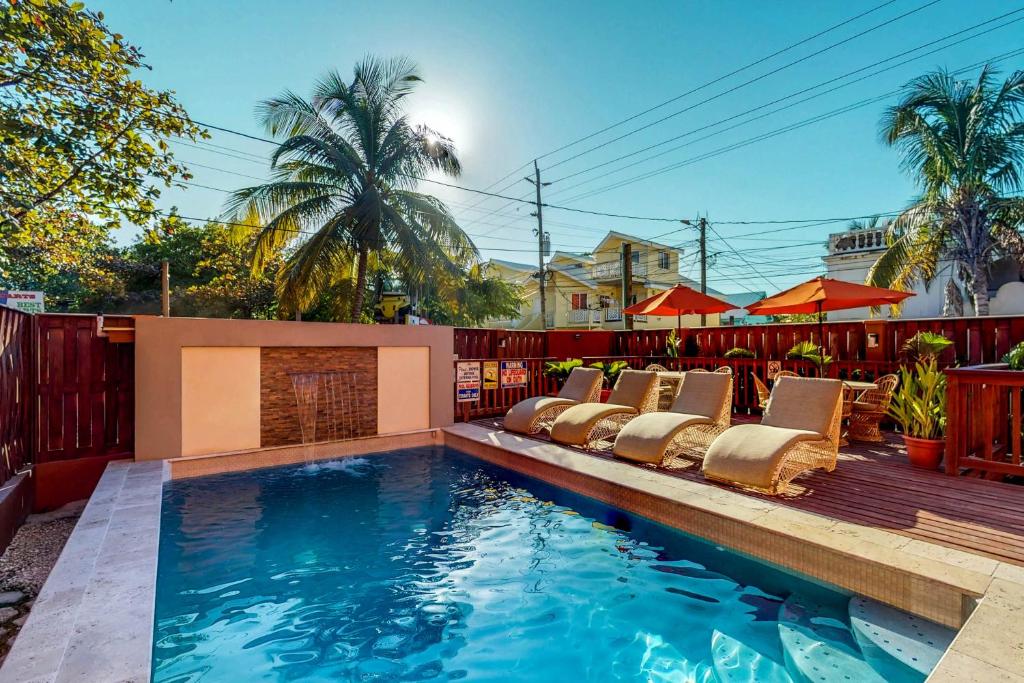 a swimming pool with lounge chairs next to a fence at Hummingbird Home Suites in San Pedro