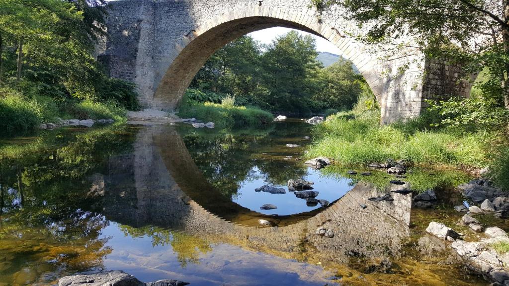 a bridge over a river with its reflection in the water at Camping Les Berges Du Doux in Colombier-le-Vieux