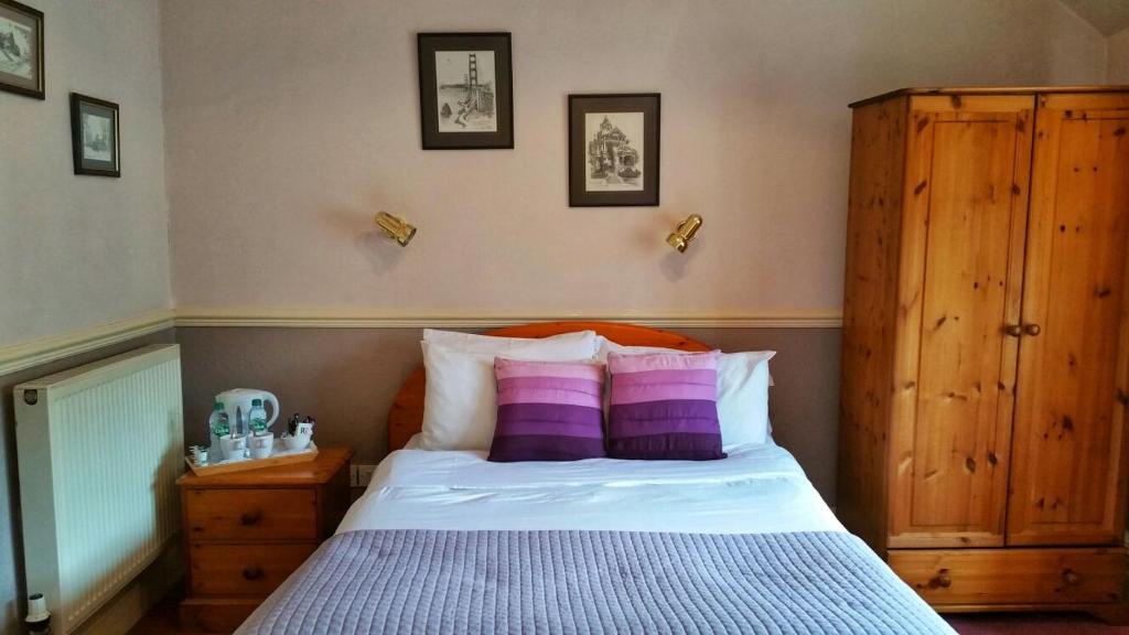 a bedroom with a bed with purple and white pillows at Kinder Lodge in Hayfield