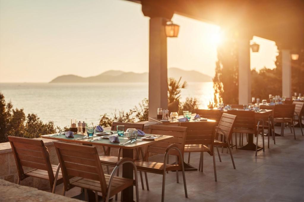 a restaurant with tables and chairs with the ocean in the background at Sun Gardens Dubrovnik in Dubrovnik