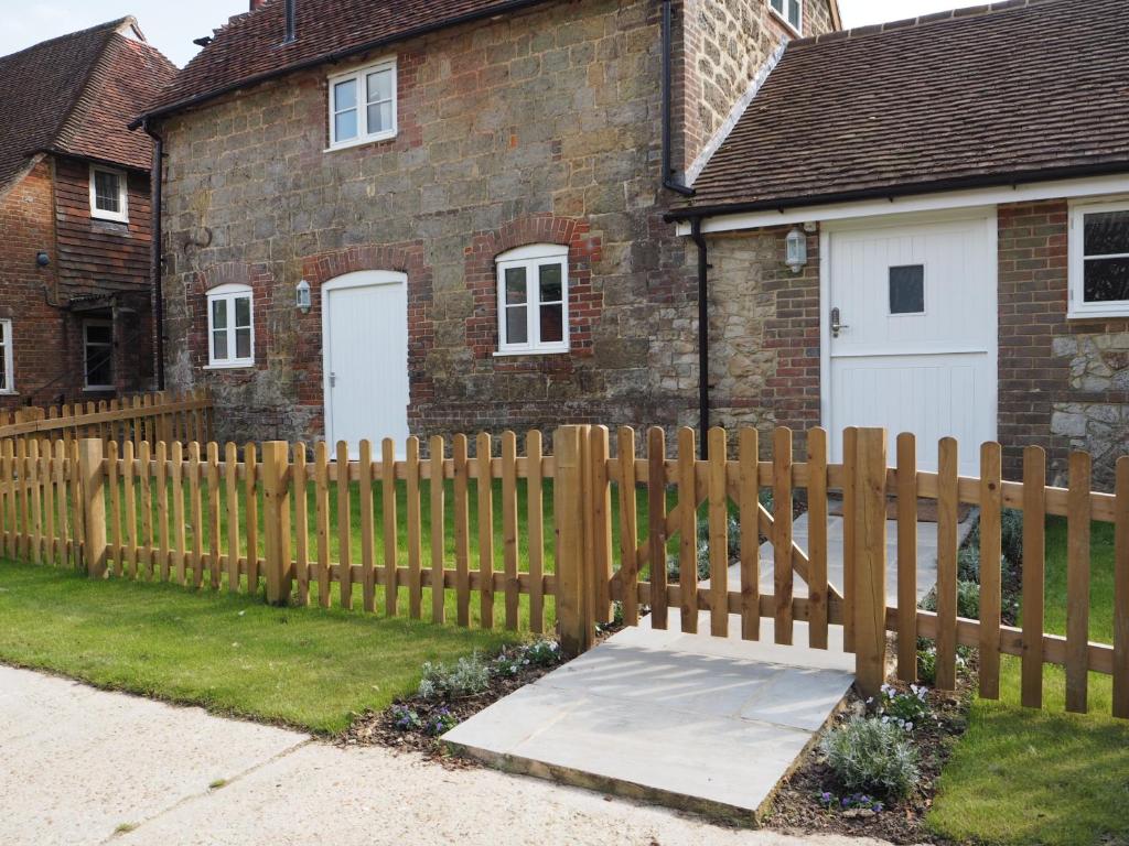 une clôture en bois devant une maison dans l'établissement Old Stables, à Pulborough