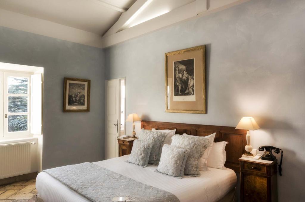 1 dormitorio con 1 cama con sábanas y almohadas blancas en Le Clair de la Plume - Teritoria, en Grignan
